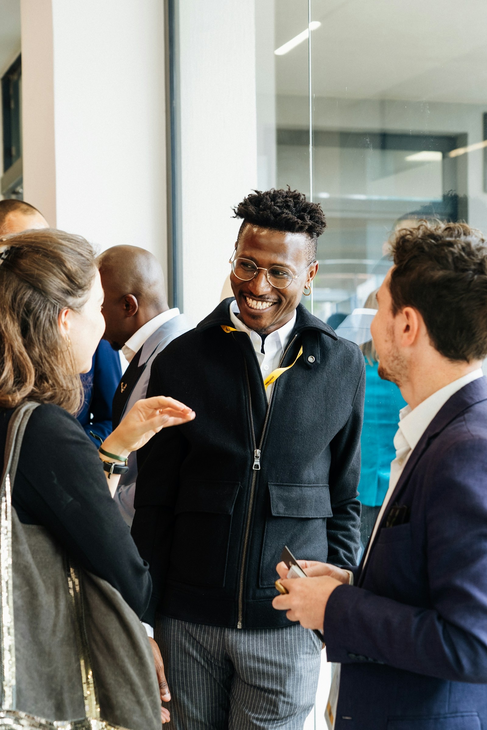 Colleagues in an easy, open conversation in a bright, glass-walled space