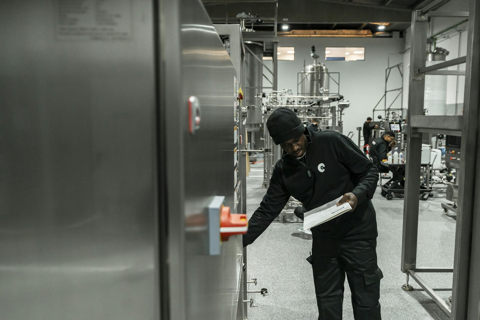 A worker in black checking equipment in a steel processing facility